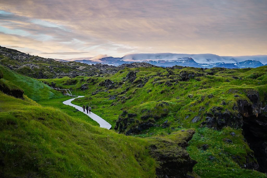 rnarstapi–Hellnar part menti túraútvonal a Snæfellsnes-félszigeten, zöld völgyekkel és vulkanikus sziklákkal – nyári kirándulás Izlandon.