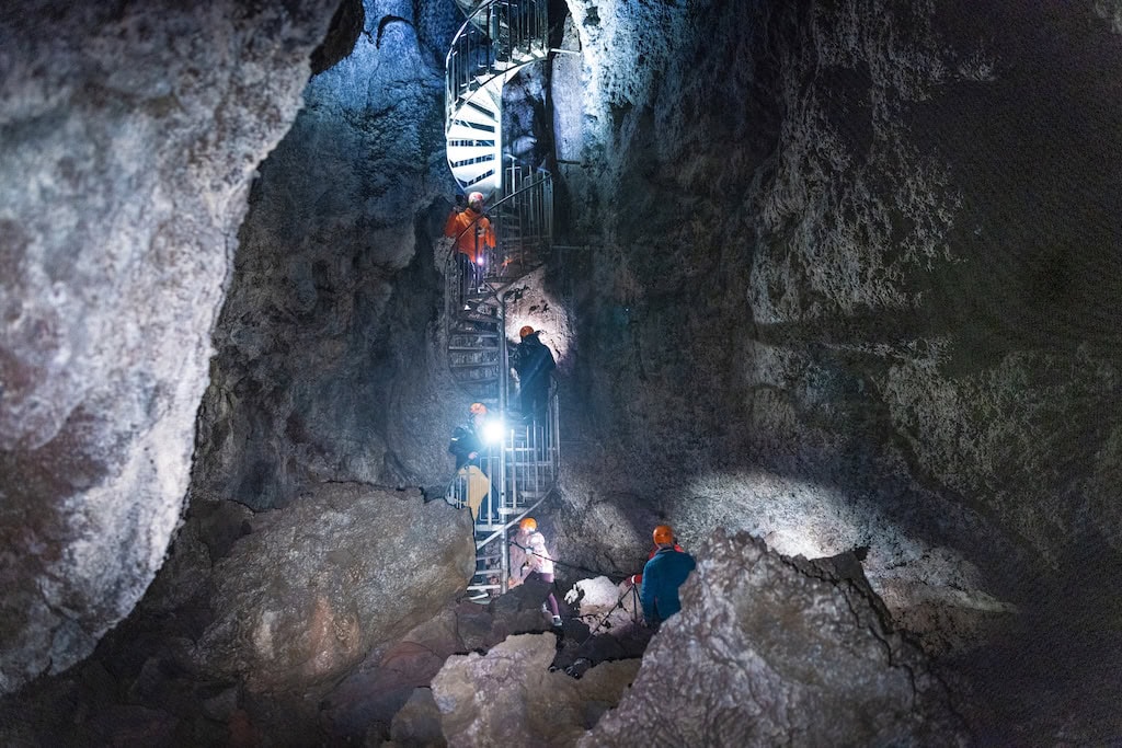 Lépcső a Vatnshellir lávabarlang mélyébe, túravezetőkkel és lámpafénnyel