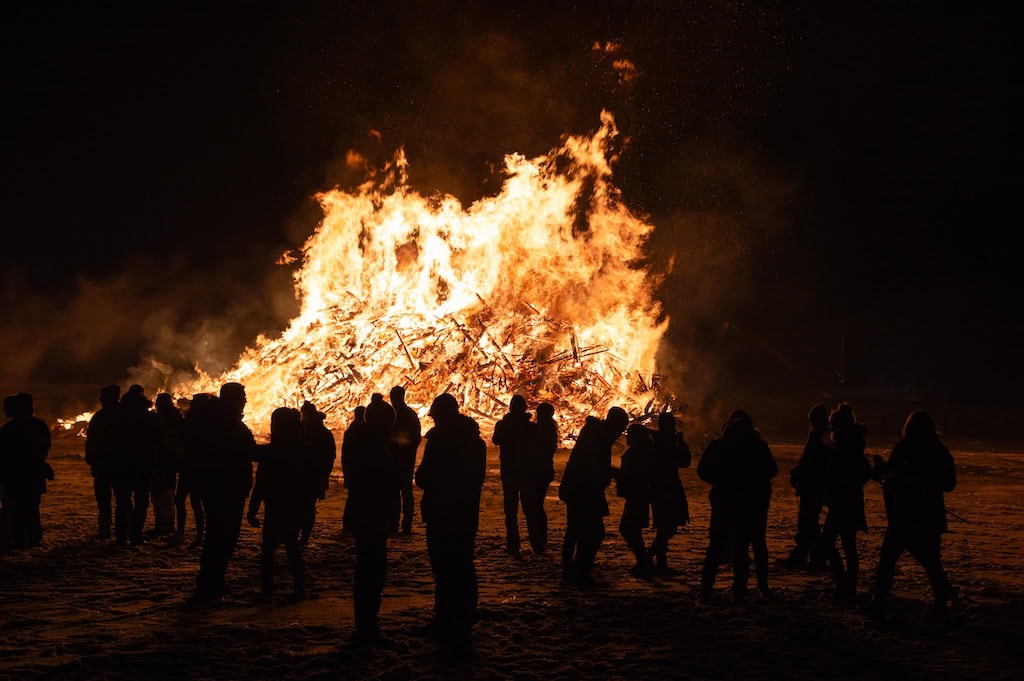 Emberek a hatalmas máglyarakás körül szilveszterkor