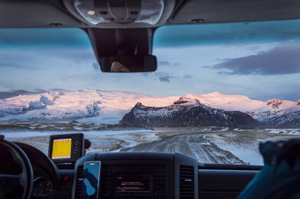 Kilátás egy autó szélvédőjén keresztül havas hegyekre