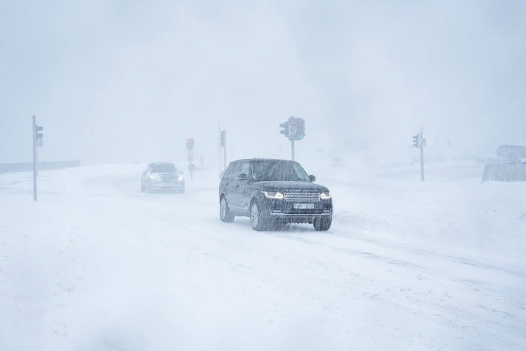 Autó halad jeges, hóval borított úton rossz látási viszonyok között. Izlandon