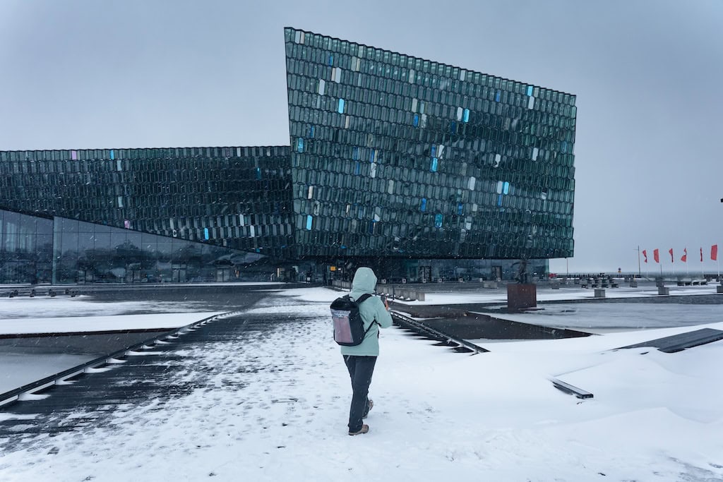 Harpa koncertterem előtt sétáló ember hóesésben