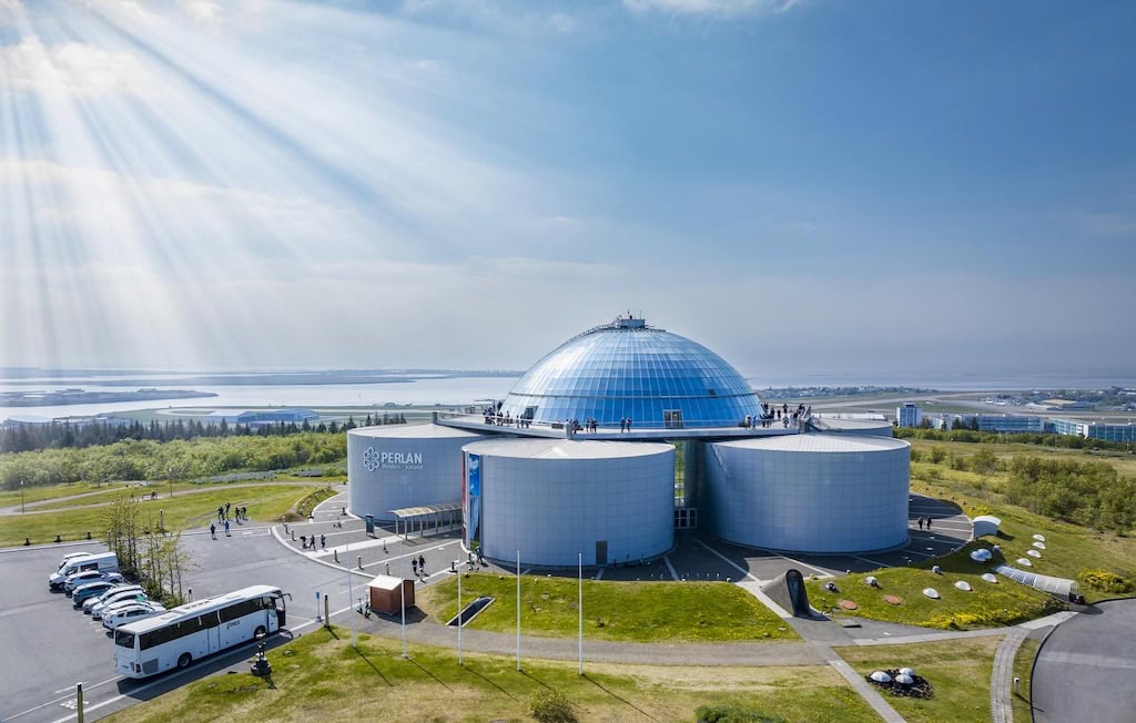 Perlan múzeum Reykjavíkban napsütésben, kupolás épülettel és kilátóval